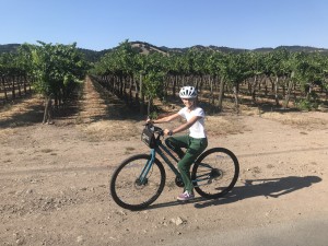 Natalia biking in front of grape vines